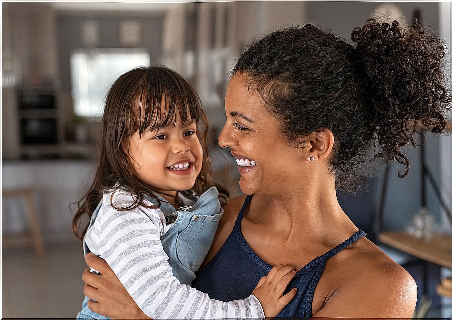 Mother hugging her daughter with a happy smile.