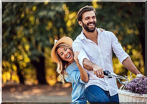 Couple with great enthusiasm riding a bicycle.