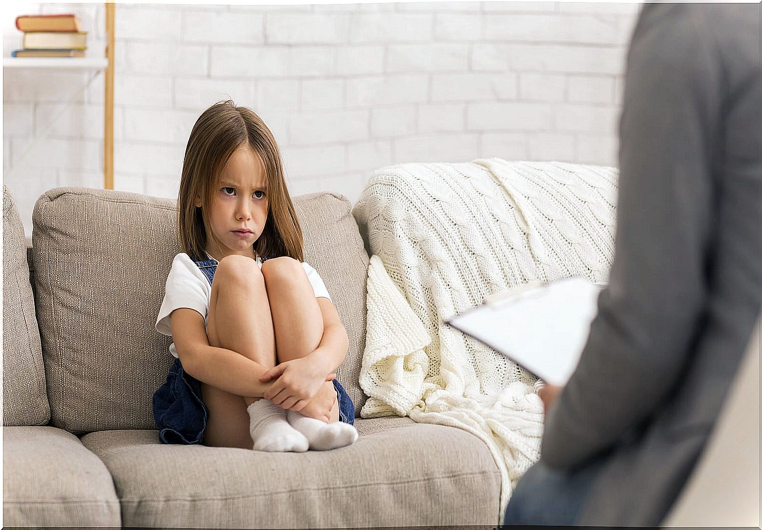 Angry little girl sitting on the sofa because her mother has scolded her.