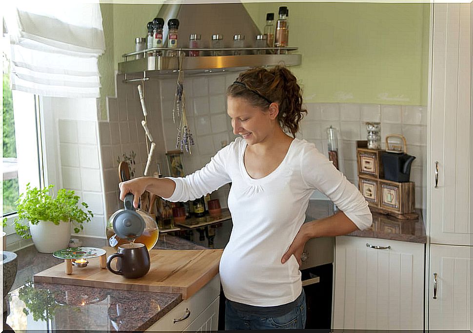 Pregnant woman in her kitchen making herself an infusion.