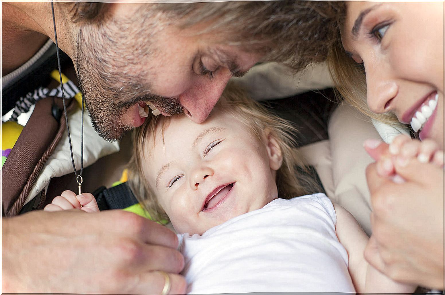 Parents playing with their baby and making him laugh to promote secure attachment.