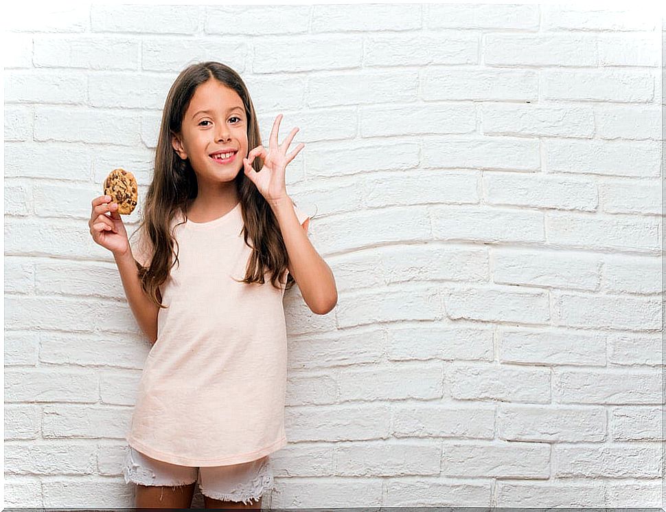 Girl receiving a cookie as positive reinforcement for her good behavior and the stickers received in the token economy system.