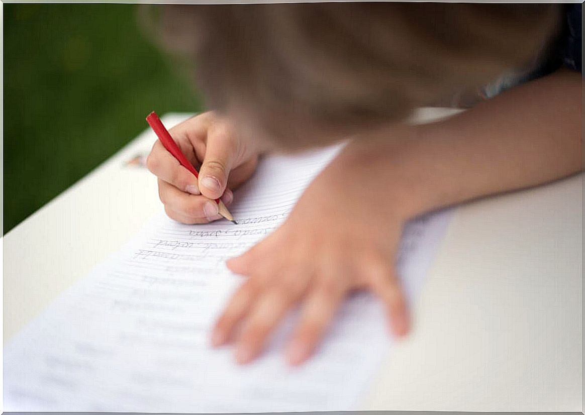 Child learning to write thanks to the Montessori guideline.