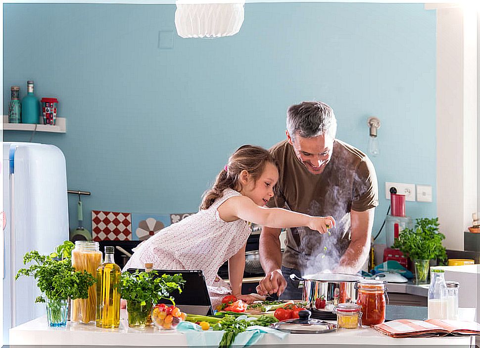 Father and daughter cooking healthy and cheap recipes.