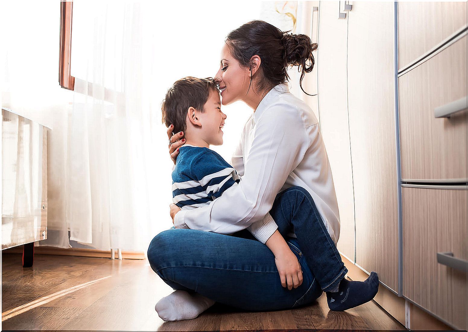 Mother giving a hug and a kiss on the forehead to her son thanks to connected parenting.