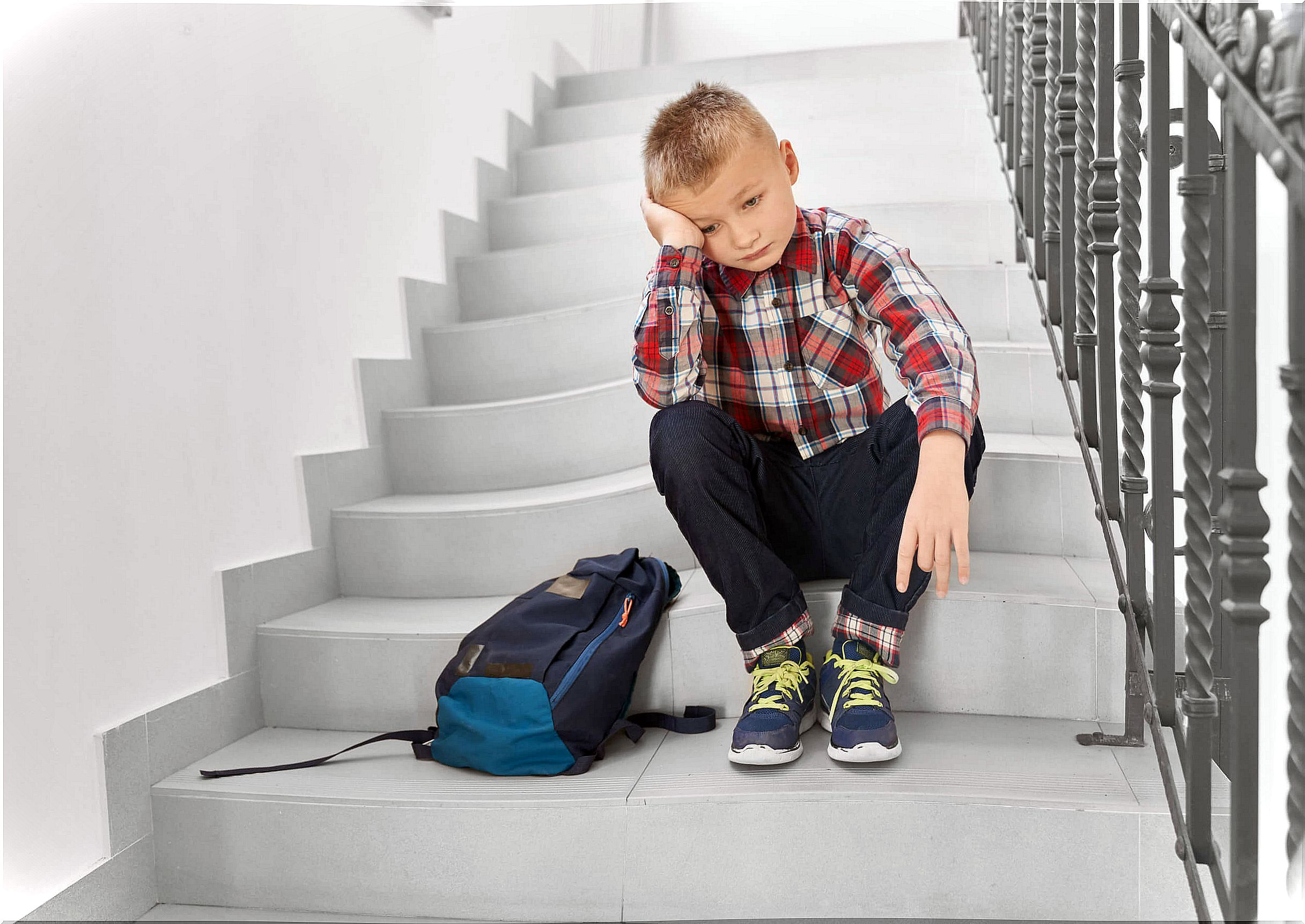 Boy sitting on the stairs of the school with fear of failure.