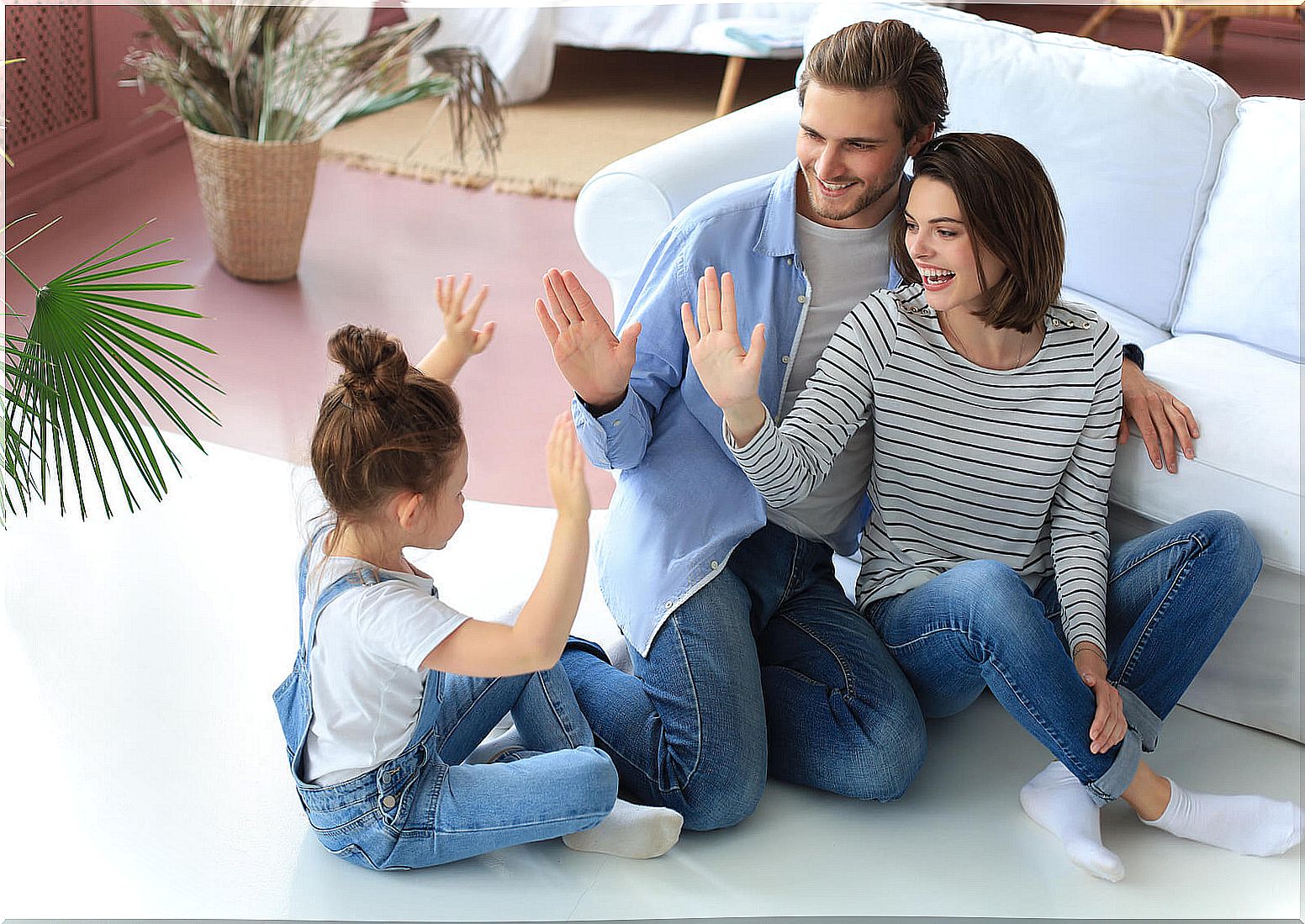 Parents playing with their daughter sitting on the floor.