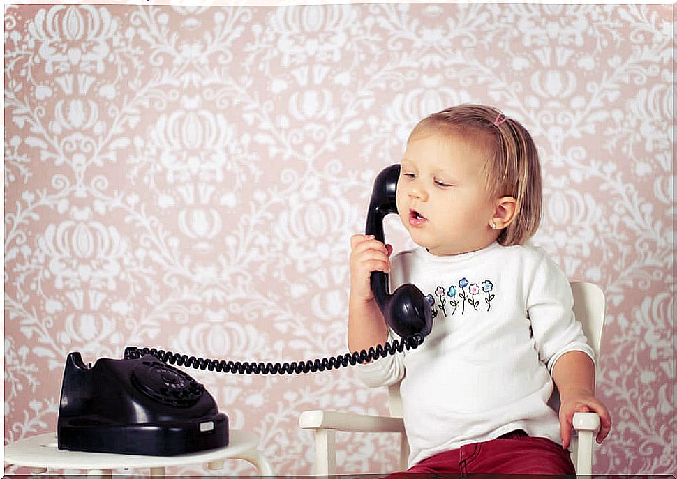 Baby girl talking on an old phone for language development.