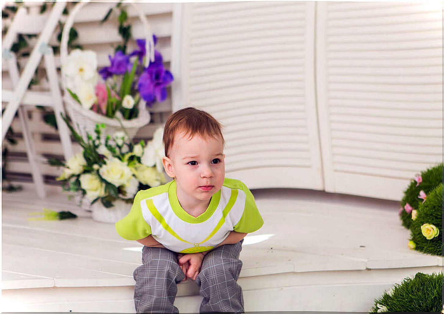 Child with a tummy ache sitting on a step.