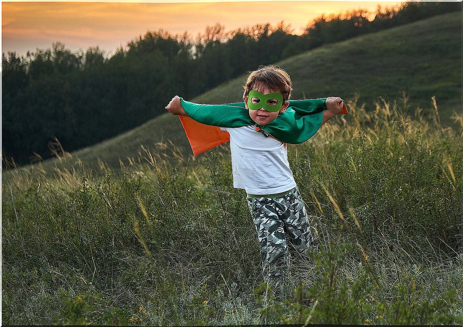 Boy dressed as a superhero in the field to develop his imagination and creativity.