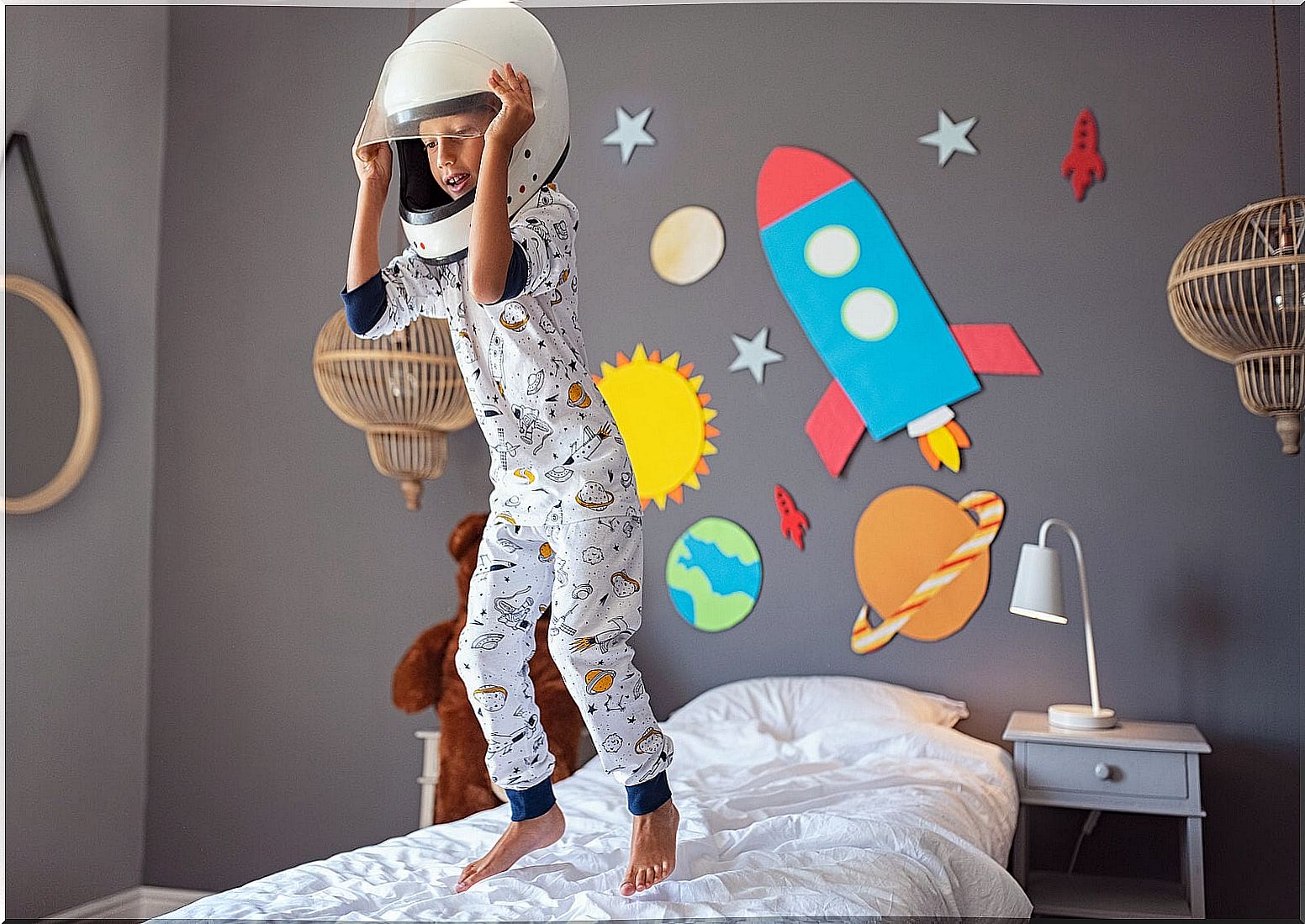 Boy jumping on the bed dressed as an astronaut.