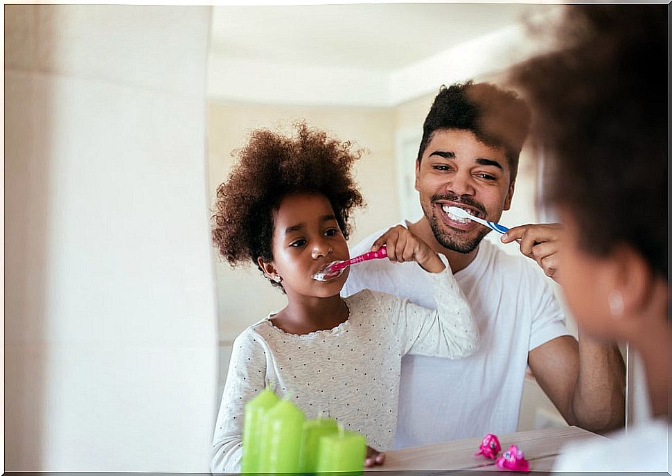 Father and daughter brushing their teeth to maintain the daily routine.